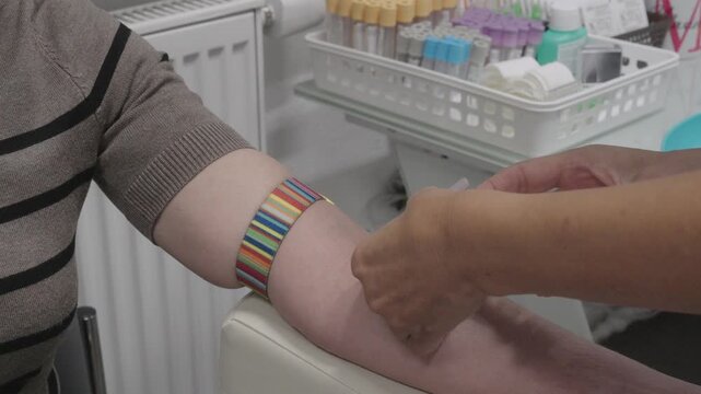 Close-up of a venous blood collection procedure. A healthcare worker takes a blood sample from a patient's arm using medical equipment