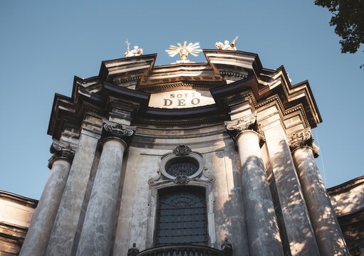 Catholic cathedral in Lviv, Uraine. Majestic church facade on blue sky background. Religious architecture. Ancient stone dome in sunlight. Religion concept. Closed door to the cathedral. 
