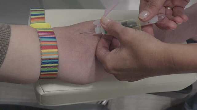 Close-up of a venous blood collection procedure. A healthcare worker takes a blood sample from a patient's arm using medical equipment