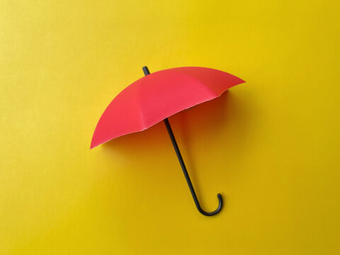 Red umbrella isolated against a bright yellow background, creating a bold minimalist concept for rain protection, weather and seasonal design.