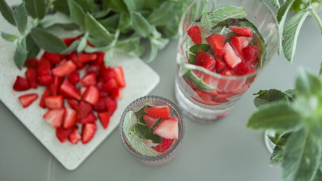 Composition of sliced strawberries on plate glass with ice and fresh mint leaves. JPG