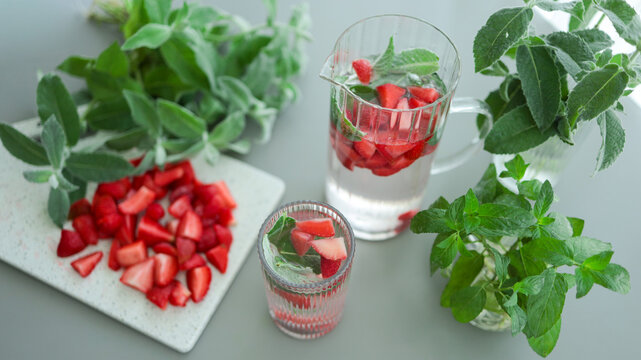 Top view of sliced strawberries plate with mint cocktail glasses and fresh green herbs. JPG