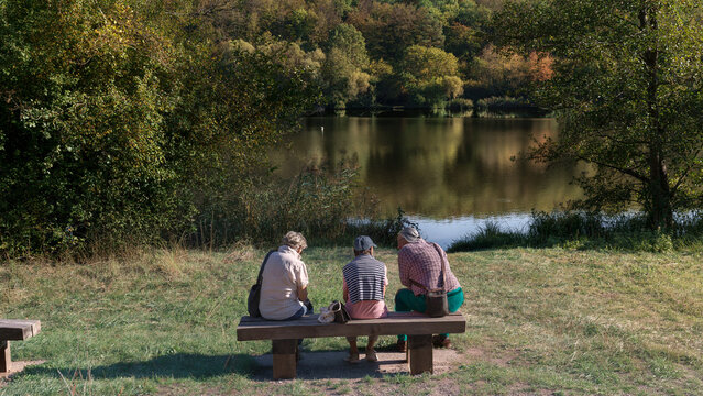 trio de personnes assis sur le banc pr&eacute;s de l'eau