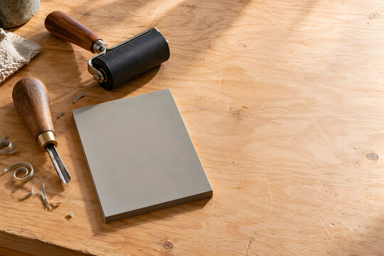 Linocut block carving tools and ink roller on workbench