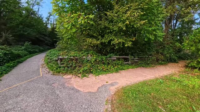 Walking Along Concrete Pathway Navigating Sharp Corner Turn Through Lush Greenery Of Urban Park, Varese, Italy - POV VIDEO - NO AUDIO