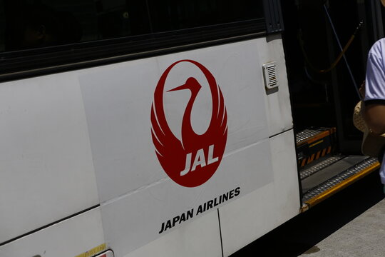Japan Airlines logo on airport tarmac shuttle bus.
