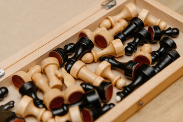 playing chess on chessboard, black and white chess pieces lying in box before or after game beginning, angle view © Anton Pentegov