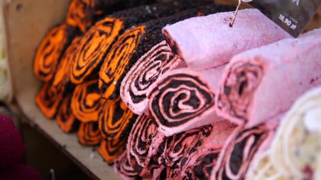 Decorative artisan candies are arranged closely in colorful confectionery display. Pink and orange sweets feature bold swirls, giving this handcrafted selection inviting presence in candy shop.