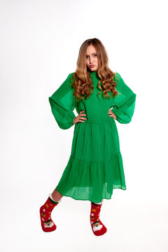 dissatisfied teen girl in green dress making duck face and posing hands on hips on white background