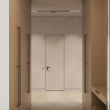 Bright minimalist hallway with built in wardrobes, concealed doors, warm beige finishes and herringbone wood flooring in a contemporary apartment.
