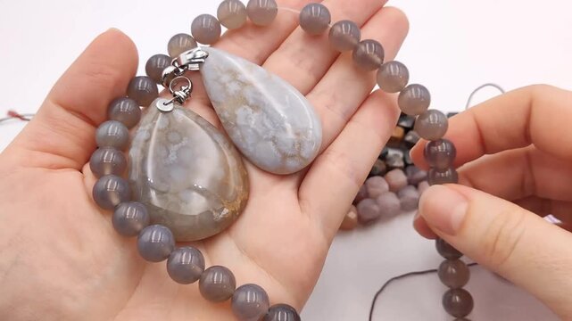 Assortment of polished natural gemstone pendants featuring unique mineral patterns arranged next to colorful faceted cube bead strands on a clean surface