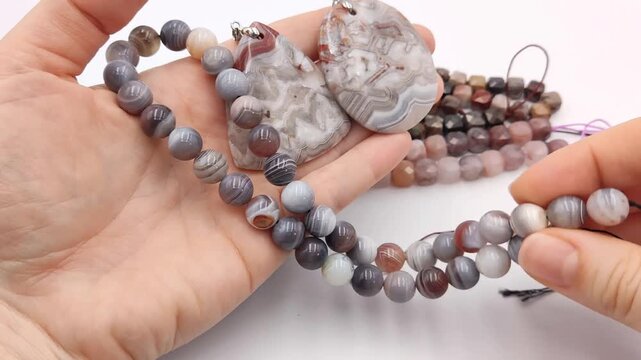 Assortment of polished natural gemstone pendants featuring unique mineral patterns arranged next to colorful faceted cube bead strands on a clean surface