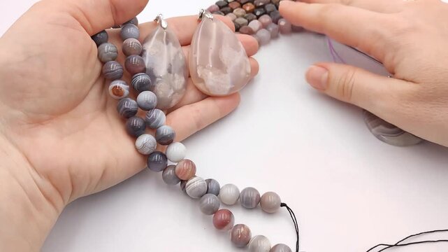 Assortment of polished natural gemstone pendants featuring unique mineral patterns arranged next to colorful faceted cube bead strands on a clean surface