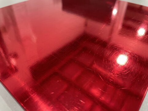 Shiny Red Metallic Surface with Reflections and Scratches.
