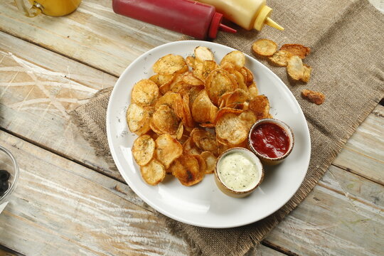 Crispy potato chips with dipping sauces on white plate
