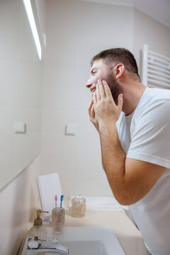 Man looking at the bathroom mirror doing morning skin care routine