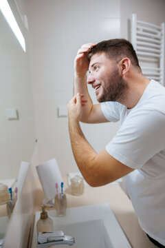 Man looking at the bathroom mirror doing morning skin care routine