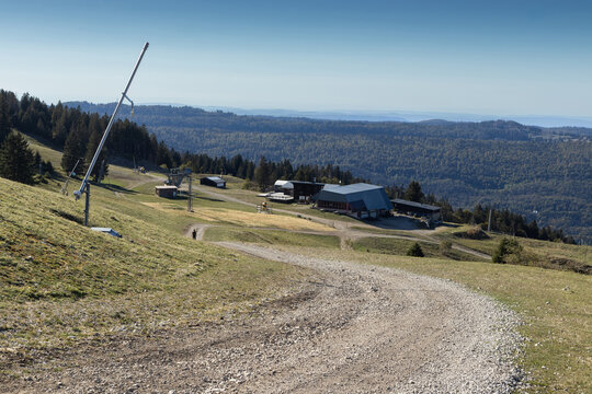 View of the L&eacute;lex-Crozet ski area at Col de Crozet in the Haut Jura, France in summer. With the top station of the Catheline cable car, snow lances and view over the Jura mountains. Copy space above.
