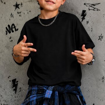 Cool boy wearing oversized black t-shirt, pants, stands by graffiti wall. Youth crewneck short sleeve t-shirt mockup. Young kid model outside, urban, city street outfit