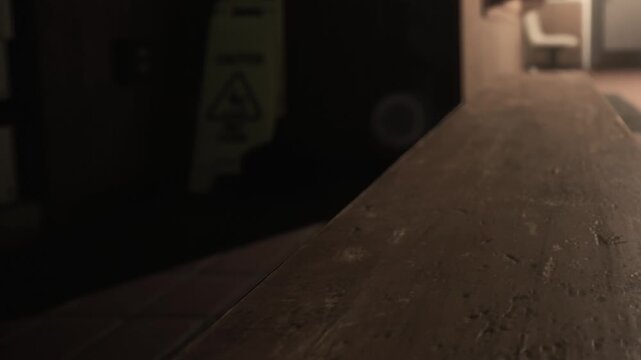 A weathered wooden surface stretches across the foreground, softly illuminated by gentle light, while shadows play in a tranquil indoor environment hinting at activity nearby.