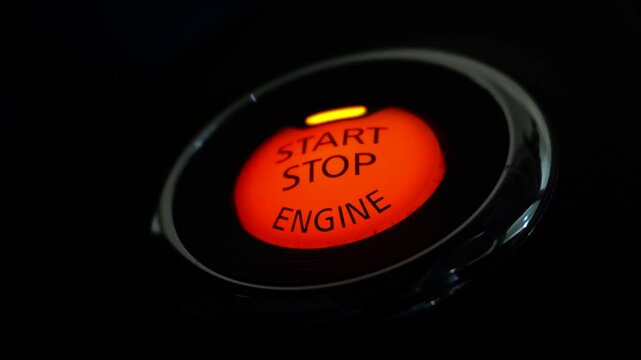 Glowing Red Start Stop Engine Button on Dashboard in Dark Car Interior