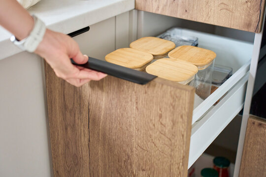 Hand opening kitchen drawer filled with transparent food storage containers