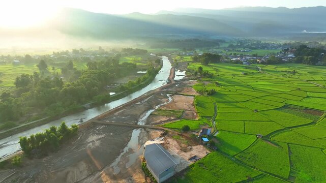 Aerial view captures muddy flood debris spreading across agricultural fields, illustrating powerful floodwater movement, landscape alteration, and threats to rural livelihoods. Nan Province, Thailand.