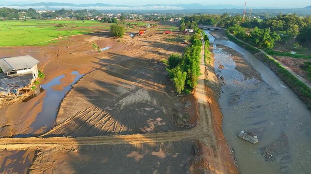 Aerial view captures rice fields buried beneath mud and sediment after severe flash flooding, illustrating agricultural devastation, soil displacement and environmental damage. Nan Province, Thailand.
