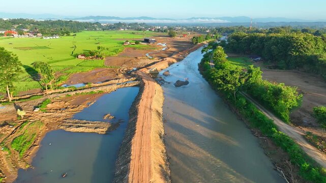 Aerial view captures traces of powerful flash floods sweeping through rice paddies, highlighting muddy debris, crop destruction, farmland damage, and natural disaster impacts. Nan Province, Thailand.
