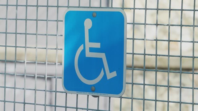Blue Wheelchair Accessibility Sign Mounted on Galvanized Steel Wire Mesh Fence