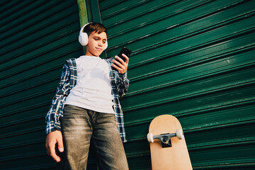 Teenager listening to music with smartphone and skateboard © djile