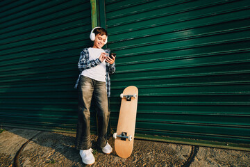 Young boy enjoying music on smartphone with skateboard © djile
