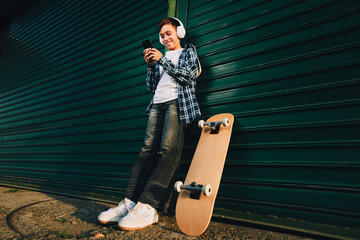 Teenager listening to music on phone leaning against wall © djile