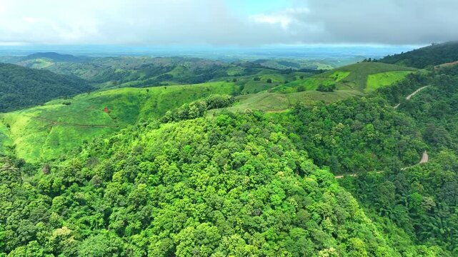 A tropical mountain forests interrupted by cleared vegetation, emphasizing land use pressure, deforestation, habitat destruction, and sustainable land management. Phrae Province, Thailand. 4k.
