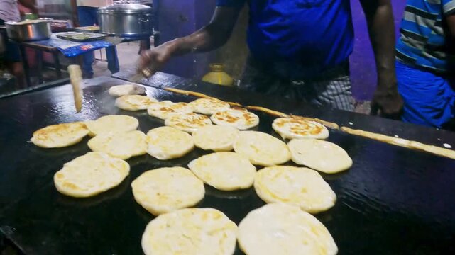 Video of a street food vendor cooking fresh parathas on a large hot griddle at a roadside restaurant in South India, showcasing Indian cuisine and everyday food preparation.