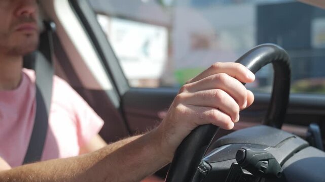 Male driver holds steering wheel while driving car in daylight