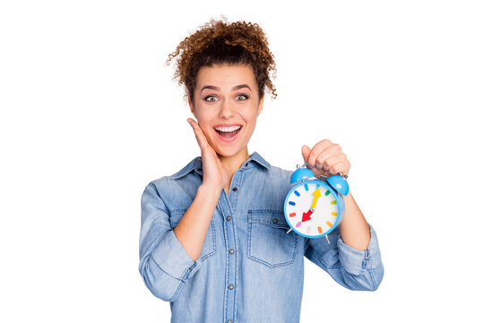 Photo of pretty wavy lady hold colorful alarm clock woke up early not late toothy smile arm on cheek wear casual denim blue shirt isolated grey color background