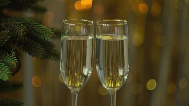 Preparing for festive Christmas or New Year feast . Woman puts two glasses of champagne on table. Celebrating New Year.