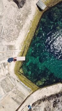 Man jumping into crystal clear water from a diving board in Calo s Estaca Mallorca