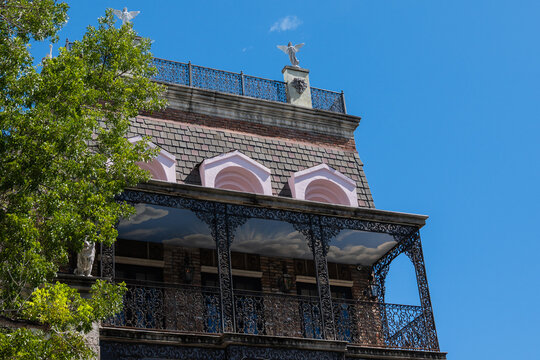 Historic Building with Ornate Iron Balcony and Decorative Rooftop Statues