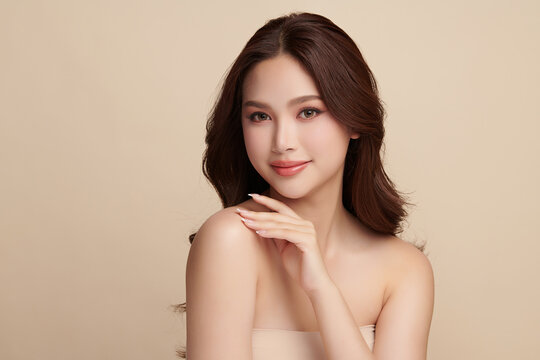 A beautiful young Asian woman with clean, fresh skin against a beige background. Skincare, facial treatment, cosmetology, beauty, and spa. An elegant portrait of an Asian woman.