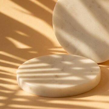 Natural marble circles arranged for luxury cosmetic display purposes featuring soft sunlight patterns cast across the beige surface to create a warm and serene atmosphere for premium skin care