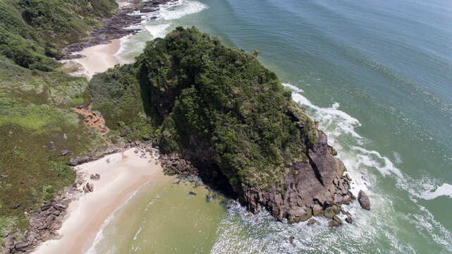 Aerial view of rocky island covered by forest and small hidden beach at Canto do Morcego, Praia Brava, Itajai, Brazil