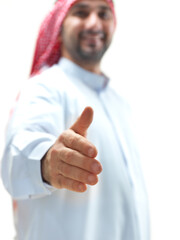 Medium shot of smiling Arab businessman wearing traditional thawb and ghutra offering handshake greeting.    © Fatih