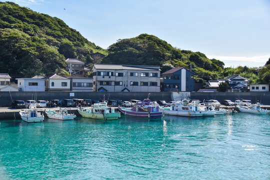 エメラルドグリーンの透き通る海に幾重もの船が繋がれた柏島の港風景
