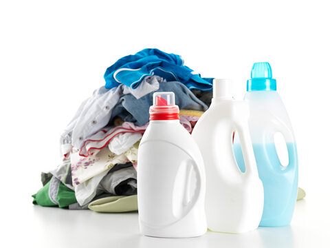 Pile of colorful clothes with multiple laundry detergent bottles against white background.