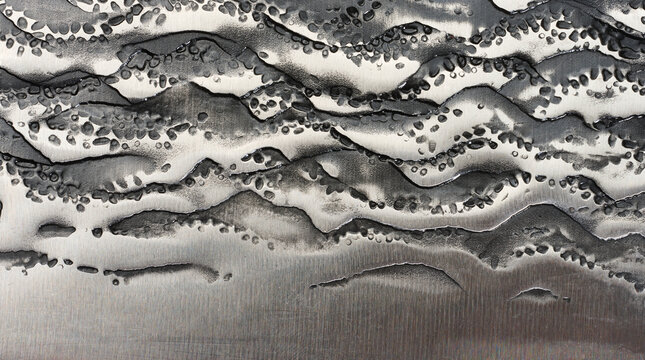 Close-up of the forged steel texture on a knife blade with a raised dark pattern.