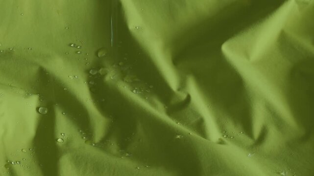 Drops of water are dripping on vibrant green hydrophobic fabric surface