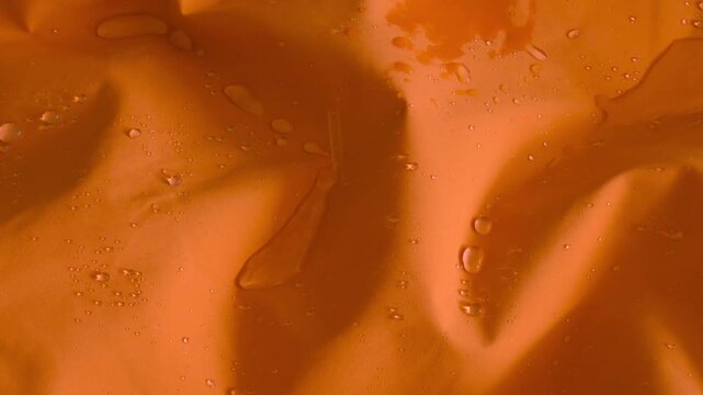 Drops of water are dripping on vibrant orange hydrophobic fabric surface
