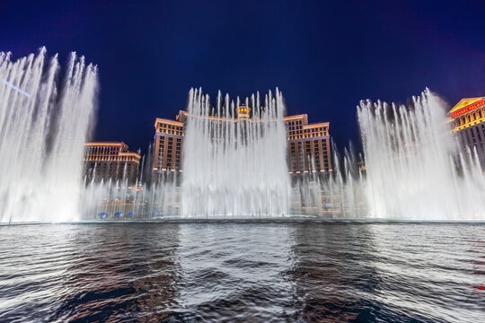 Beautiful view of Bellagio fountain show at night with Bellagio, Caesars Palace and Cosmopolitan hotels. Las Vegas. USA. 